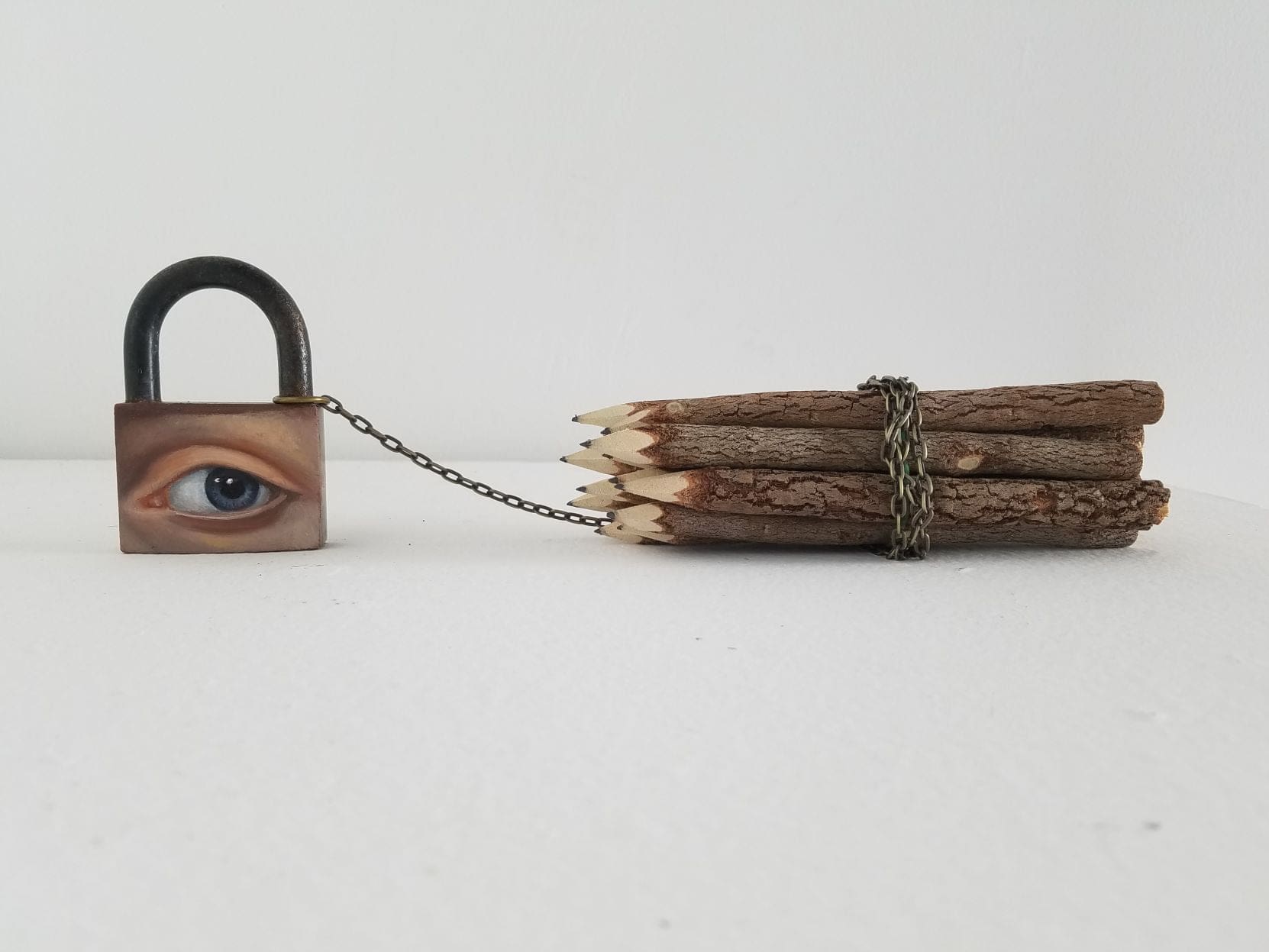 [Alexandra Dillon, The Burden of Drawing, 2020. Oil on big padlock, rustic pencils, chain. 15 x 2 in.]