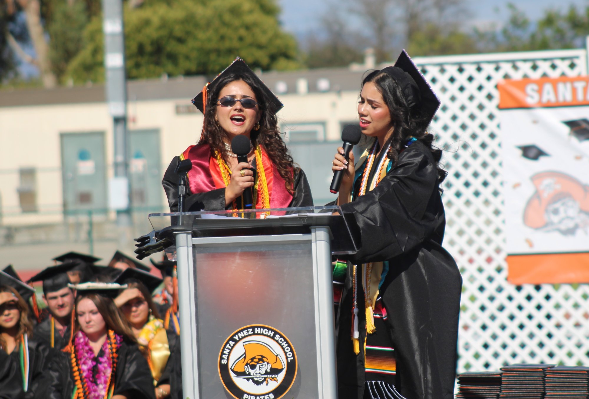 Santa Ynez High graduating seniors Addisynn LaLiberte (left) and Anelly Tovalin sing a duet of Fleetwood Mac's "Landslide" during the 2026 graduation ceremony May 29 at Rio Memorial Field. Photo by Mike Chaldu/SYVS