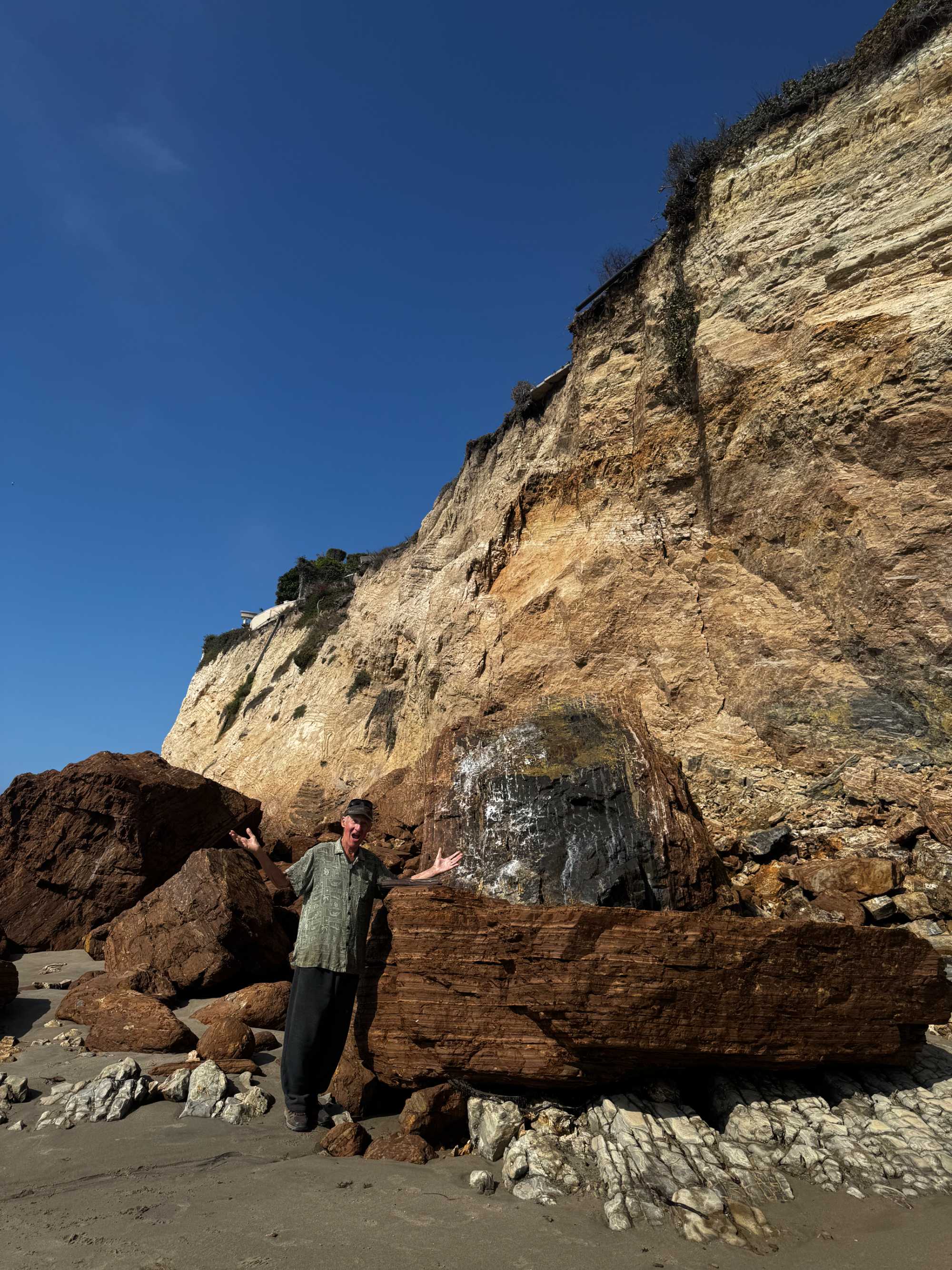 Eric “Rockman” Pierson, who grew up in Malibu, is shown among some boulders that fell onto Little Dume Beach from the cliff during the recent rockfall. Photo by Barbara Burke