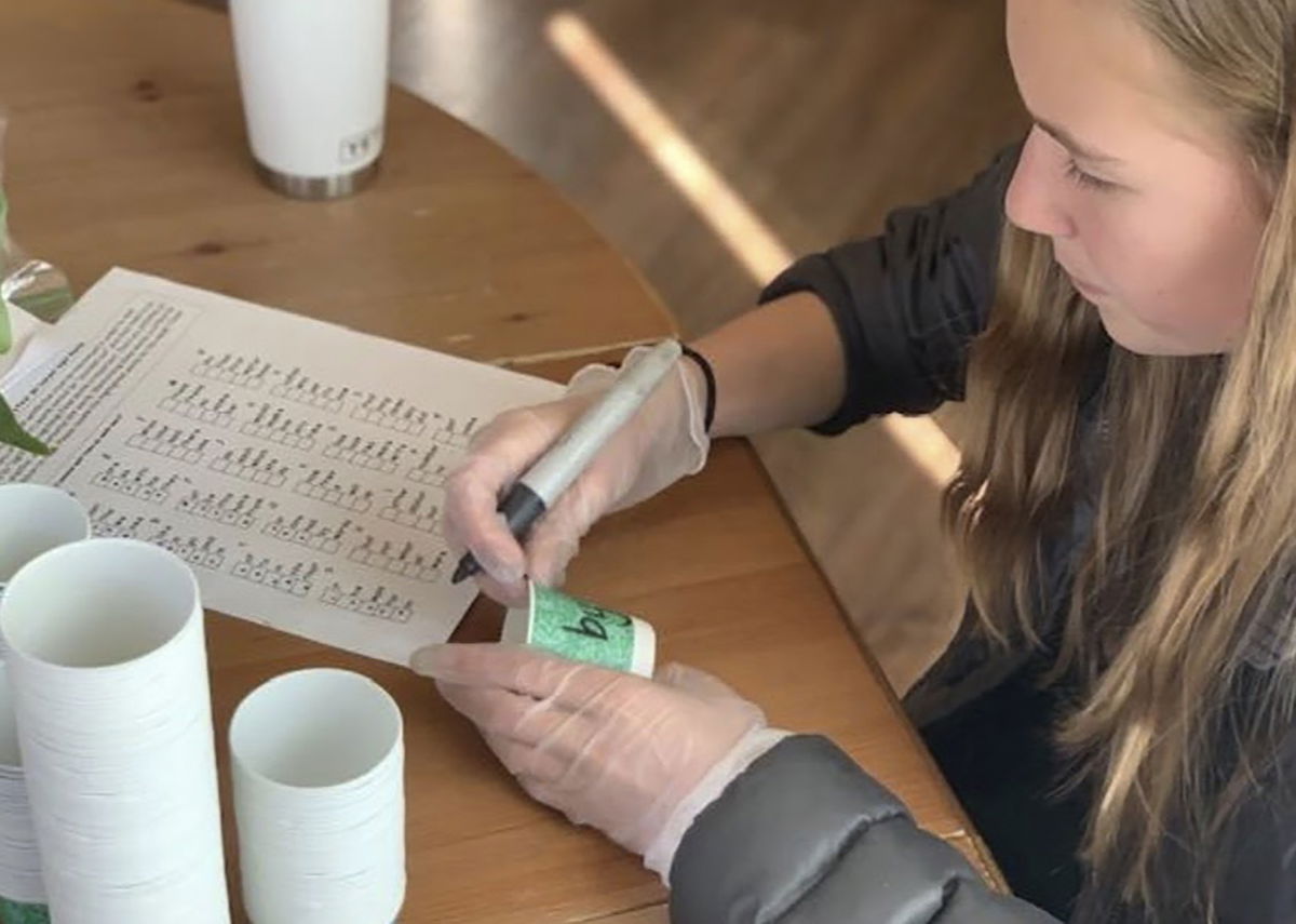 Olivia Heinbach labels snack cups with sight words.